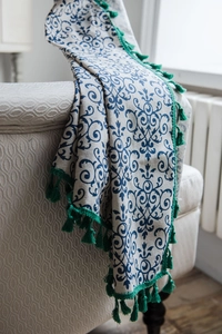 Close-up of blue floral print curtain with green tassels on a cozy armchair