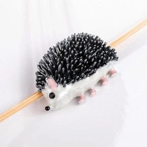 Macro shot of cute enamel hedgehog brooch with detailed black spikes and white belly