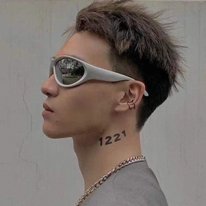 Close-up of silver futuristic Y2K wrap-around sunglasses and punk metal jewelry