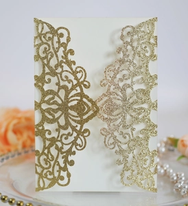 Macro detail of laser-cut wedding invitation with gold glitter floral hollow patterns