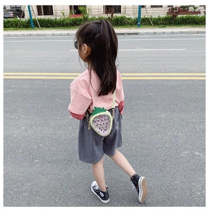Detail of sequined strawberry crossbody bag for girls with adjustable strap worn outdoors