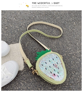 Details einer erdbeerförmigen Paillettentasche mit grünem Ledergurt und goldener Schnalle
