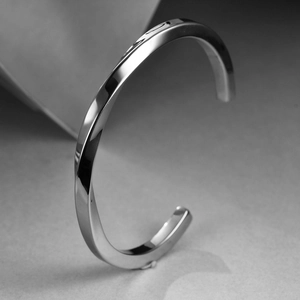 Close-up of a minimalist twisted silver cuff bracelet with a high-polished mirror finish
