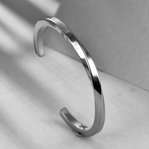 Macro view of polished stainless steel Mobius twist open bangle with glossy silver finish