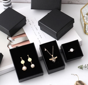 Linen textured black jewelry boxes showing elegant earrings, necklace and ring set