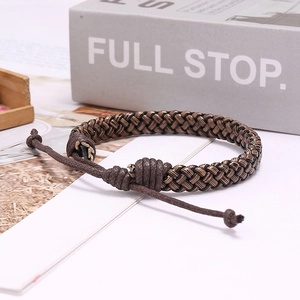 Detail of adjustable braided leather bracelet in brown tones on a minimalist white desk
