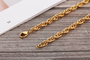 Detailed close-up of a gold rope chain necklace with a secure lobster clasp on wood