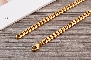 Macro view of chunky golden Cuban chain necklace with a classic lobster clasp closure