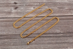 Flat lay of a gold Cuban link chain with lobster clasp on a vintage wood background