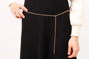 Detail of golden circle-link body chain with pearl accent on a black dress