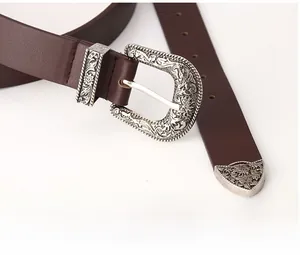 Detailed macro shot of vintage silver floral engraved buckle on dark brown leather belt
