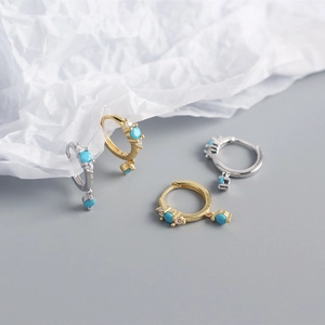 Detailed view of gold and silver S925 sterling silver huggie earrings with turquoise