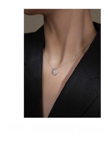 Close-up of S925 sterling silver moon and star pendant necklace on a model in a black suit
