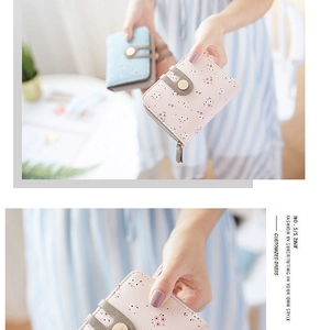 Detail of floral printed mini wallet with zipper closure and decorative snap strap