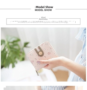 Detail of pink floral short wallet with zipper closure and gold accent held in hand