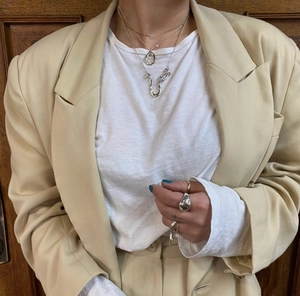 Detail of layered 925 silver pearl necklace and thick polished ring on fashion model