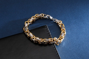 Detail of two-tone gold and silver Byzantine chain bracelet on a leather surface