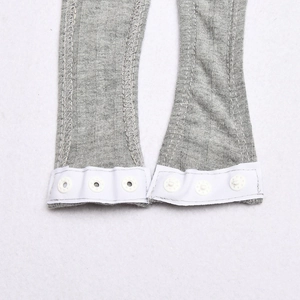 Close-up of grey ribbed fabric with white snap button closure on the bodysuit bottom