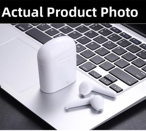 Detalle de los auriculares inalámbricos i7mini blancos y estuche sobre teclado de laptop