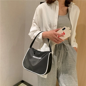 Detail of black nylon shoulder bag with white contrast piping and printed logo design