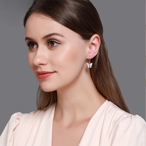 Gros plan de boucles d'oreilles papillon avec des ailes irisées rose et violet