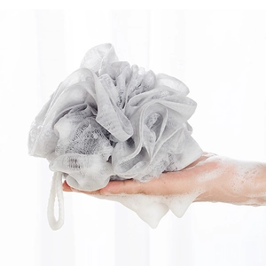 Close-up of a grey soft bath loofah creating rich white lather for skin cleaning