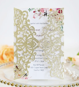 Close-up of laser-cut gold lace invitation sleeve with elegant floral inner card
