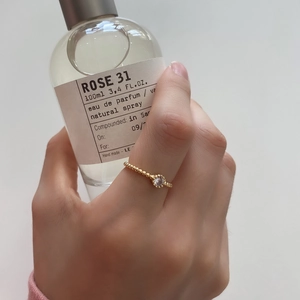Detailed shot of a gold beaded silver ring with a sparkling zircon on a woman's finger