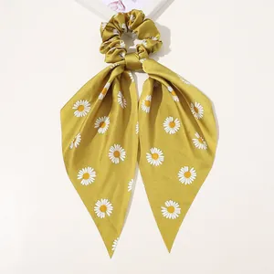 Detail of yellow satin hair scrunchie with long ribbons and white daisy floral patterns