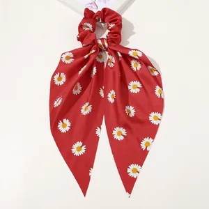 Detail view of red floral satin scrunchie with daisy print and elegant long ribbon tie