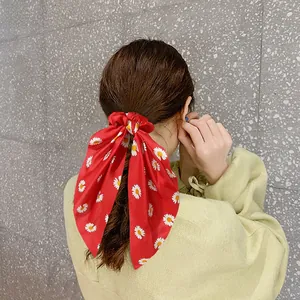 Detail of red satin bow scrunchie with white daisy pattern on female model hair