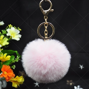 Detail of pink faux rabbit fur keychain with gold lobster clasp on black background