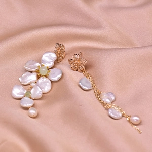 Detail of baroque pearl earrings with golden floral tassels on champagne silk