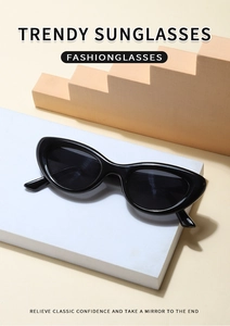 Close-up of black cat-eye sunglasses on a white stone block with geometric shadows