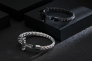 Detail of woven stainless steel bracelets with anchor clasps in black and silver finishes