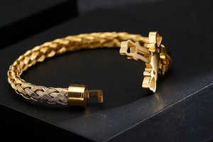 Close-up of golden woven texture bracelet featuring a detailed punk cross buckle closure