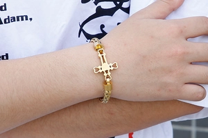 Close-up of gold stainless steel chunky chain bracelet with heart cross charm on wrist