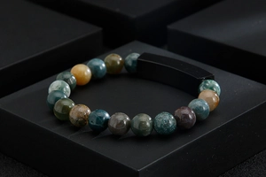 Macro shot of natural stone beaded bracelet with black matte rectangular charm on a display stand