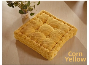 Detail of corn yellow quilted seat cushion with soft ribbed texture on wood floor
