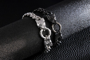 Detailed view of silver and black stainless steel wolf head bracelets on a leather display