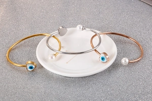 Detailed view of evil eye heart bracelets with white pearls in gold, silver and rose gold