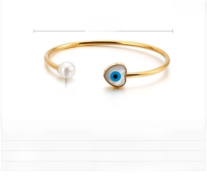 Detail of gold evil eye heart bracelet with pearl inlay and turquoise stone settings