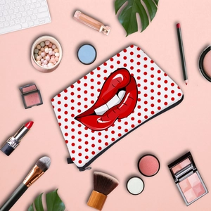 Lip print makeup bag with polka dots on pink background with cosmetics