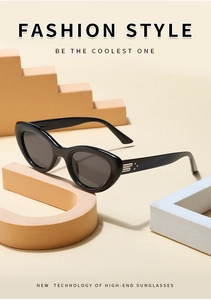 Detail shot of black cat-eye sunglasses featuring metallic temple accents on tan pedestals