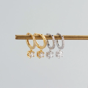 Detail of S925 sterling silver huggie earrings with sparkling cubic zirconia charms