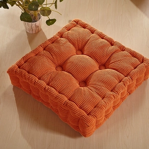 Thick orange corduroy square chair pad with nine-hole tufted design on wood background
