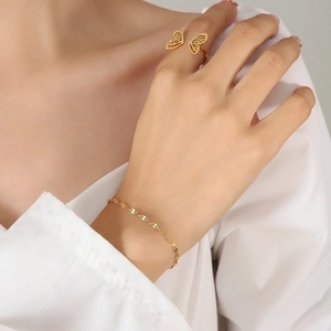 Minimalist 18K gold hollow butterfly ring and sequin chain bracelet on a model