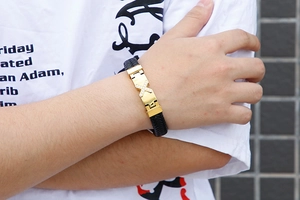 Close-up of a men's woven leather bracelet with a gold-tone diamond-set cross centerpiece