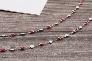 Détail de perles d'œil maléfique et breloques cœur sur une fine chaîne de taille
