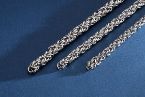Close-up of three interlocking silver stainless steel braided chains on dark blue background